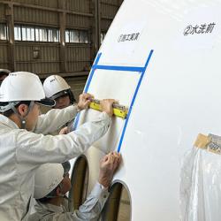 モックアップによる実演。塗膜シートを機体に圧着している様子