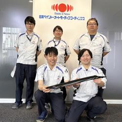 型内塗装を用いたピラー部品と開発チーム 型内塗装を用いたピラー部品と開発チーム